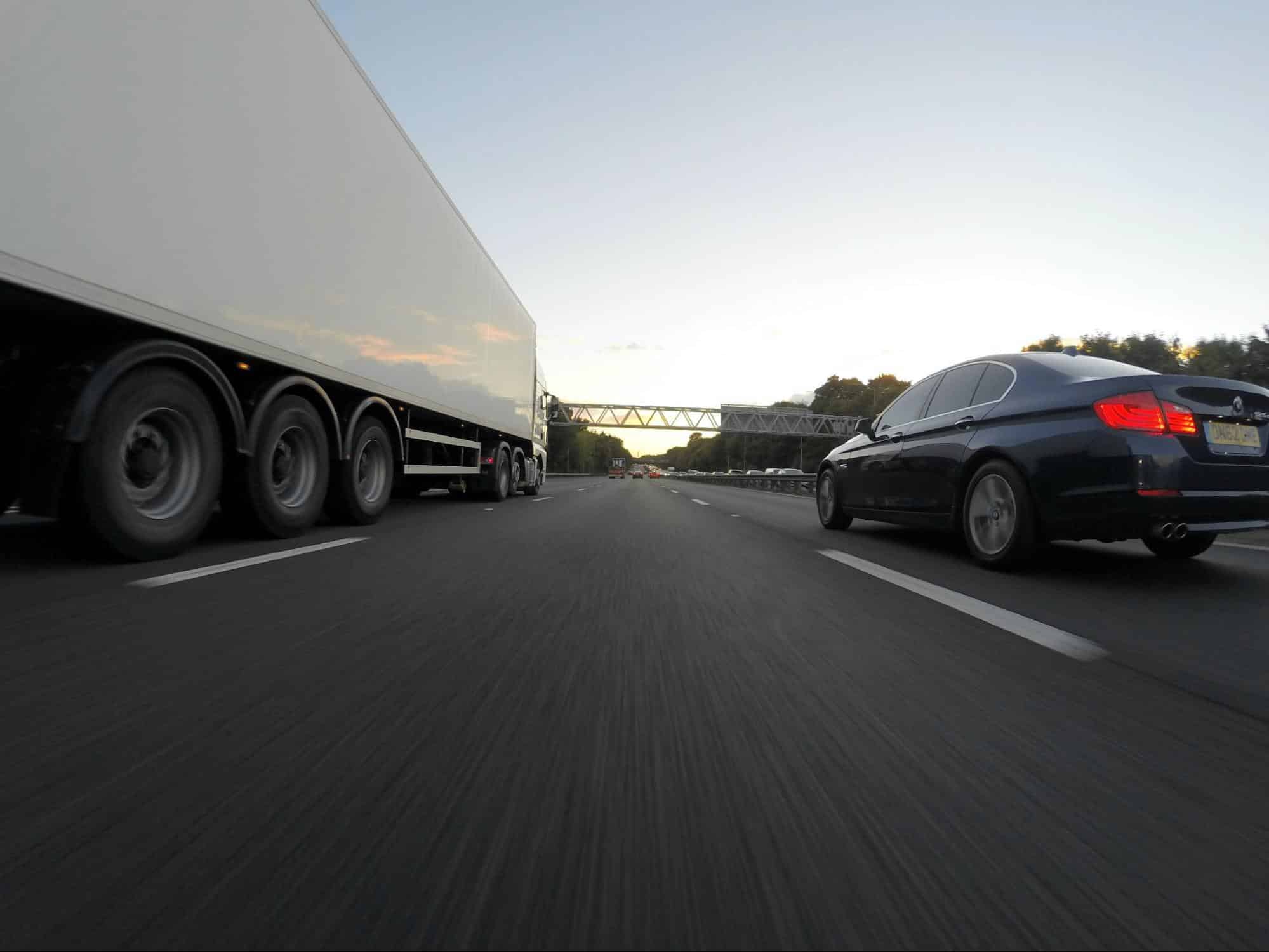 a car and a truck driving on a highway one next to another